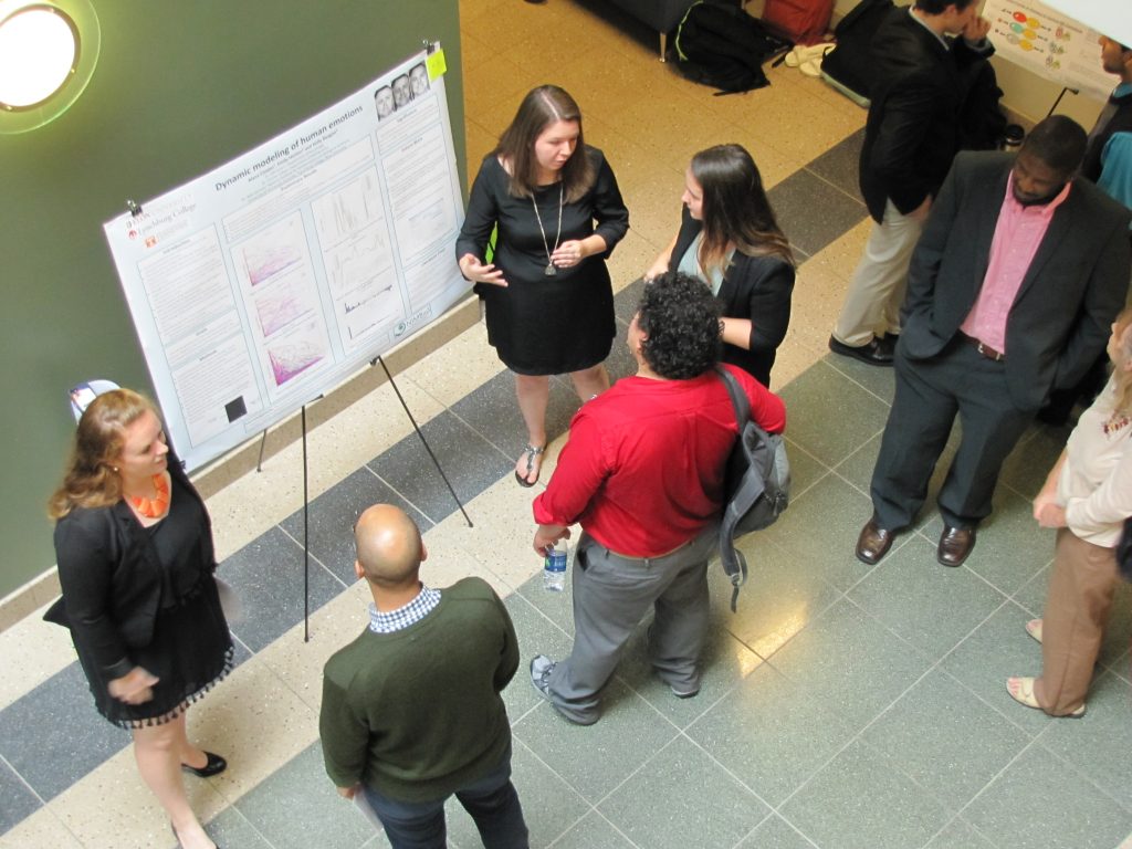 SRE participants Kelly Regan (left), Alana Cooper and Emily Horton (right of poster) present their work on dynamic modeling of human emotions.